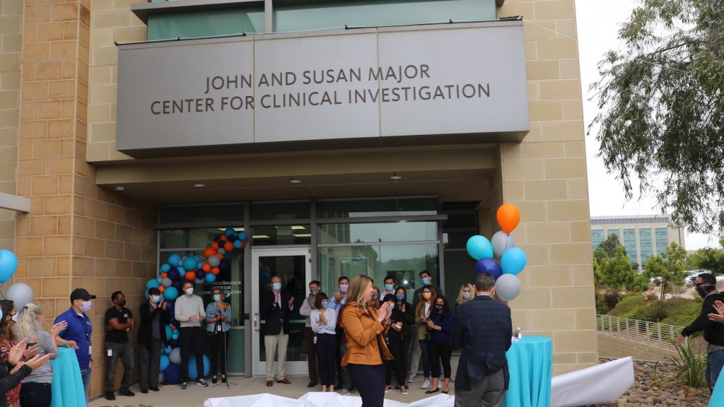 Event photo of the opening of LJI's John and Susan Major Center for Clinical Investigation. LJI staff, scientists and donors gather at the clinic doorway. They are surrounded by balloons in LJI's blue, grey, and orange branded colors