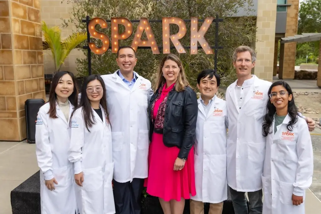 LJI President and CEO Erica Ollman Saphire stands outside the LJI building with six SPARK Awardees