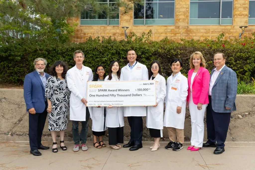 SPARK Awardees and supporters stand with a giant check awarding $150,000 to the program