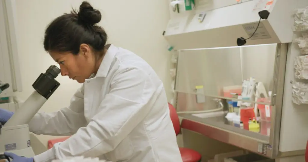 Photo of LJI scientist using a microscope in a lab setting