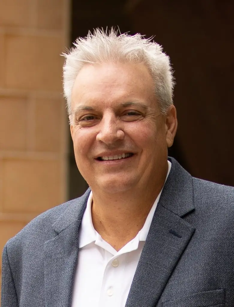 Photo portrait of Chris Benedict. He is outside the LJI building and smiling at the camera