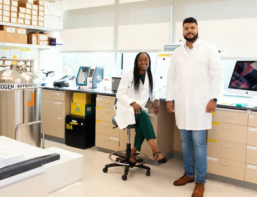 Photo of Dr. Elong Ngono and Dr. Alves in a lab setting. They are wearing white lab coats