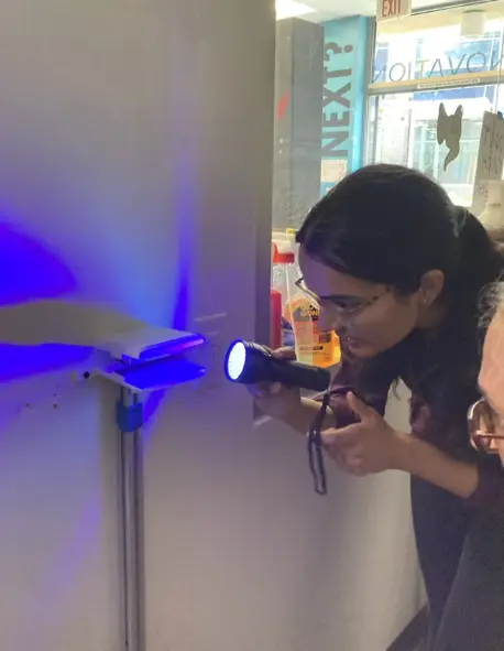 Photo of a high school student holding a black-light flashlight