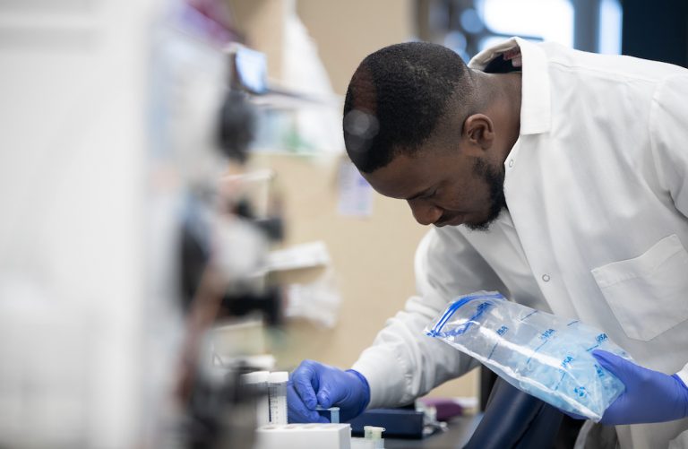 Onyeka Chukwudozie leans over a lab bench