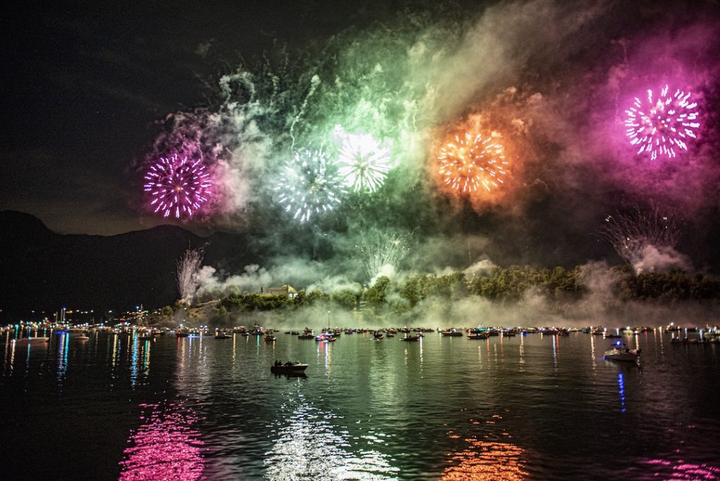 Fireworks over Lake Como. The fireworks reflect on the water. Small boats in the distance.