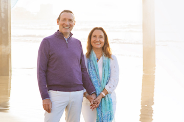 Photo portrait of François Ferré, Ph.D., and Magda Marquet, Ph.D. They are at a beach and are smiling at the camera