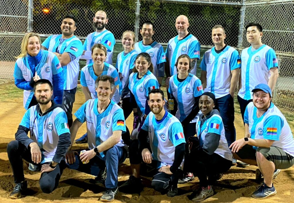 Photo of the 2018 softball team. 16 players smile at the camera. They are wearing blue and white jerseys