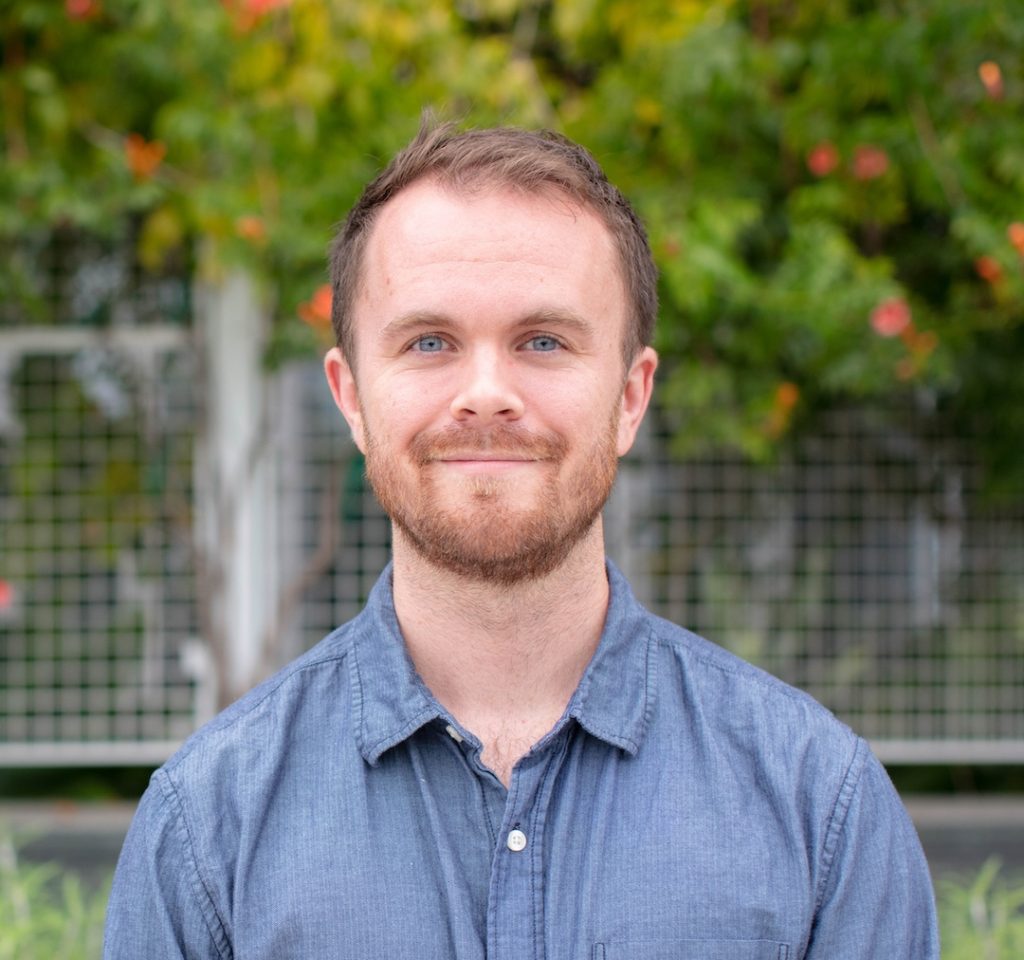 Photo portrait of Ian Mathews. He is standing outside and looking into the camera