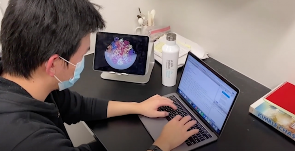 Photo of scientist looking at two computer screens