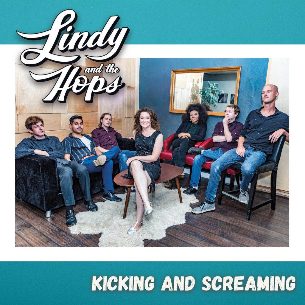 Album cover for "Lindy and the Hops." We see 7 band members sitting. Album title is "Kicking and Screaming"