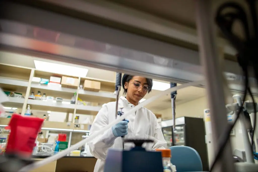 Photo of a scientist working in an LJI lab. They are holding a pipetter and working in a lab setting