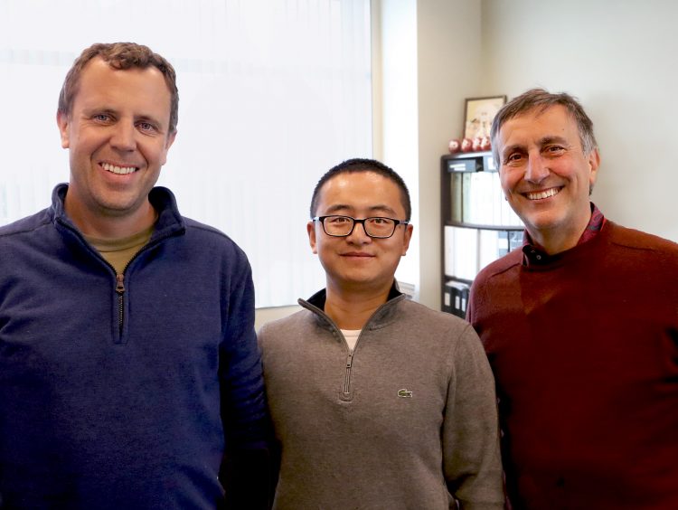 Photo of Peters, Tian, and Sette in an office setting. They are smiling at the camera